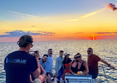 A group enjoying a stunning sunset cruise on a luxury yacht, captured by a LivBlue crew member, highlighting custom boat charters and island-hopping experiences.